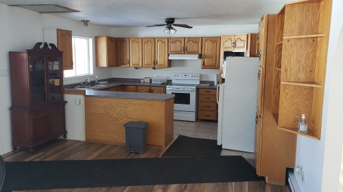 Interior view of a kitchen with wooden cabinets, stove, fridge and microwave