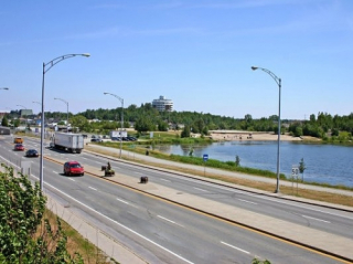 Highway with a body of water and cars on the road.