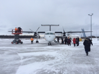 Front view of an airplane on the tarmac with people lining up to board.