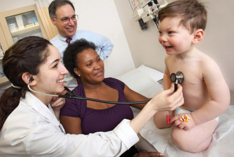 Des membres d'une équipe de soins examinent un bébé souriant