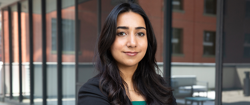 Inara Lalani poses with her arms crossed in a power blazer and green shirt.