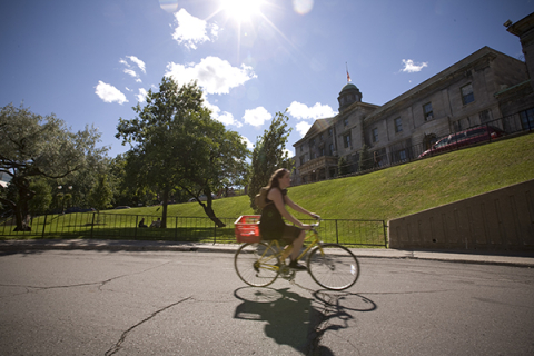 Student cycling on McGill campus in the summer