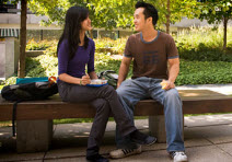 Deux étudiants discutent assis sur un banc.