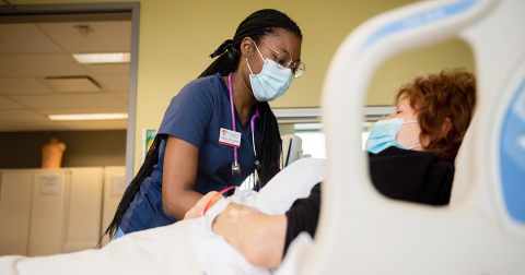 Une étudiante mcgilloise en sciences infirmières s’occupe d’une patiente allongée dans un lit d’hôpital. 