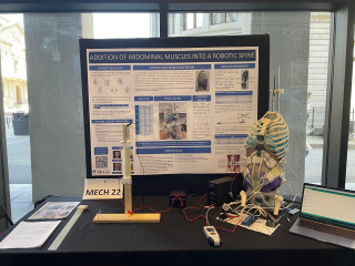 Model of a robotic spine to the right of a poster board