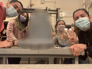 Students smiling through their masks around their digitally blurred airplane seat prototype