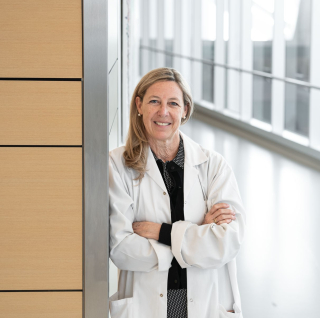Dr. Hudson in a doctor's white coat, smiling