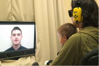 An infant testing paradigm where the infant is in its mother’s arms, while both parent and child watch a TV screen.
