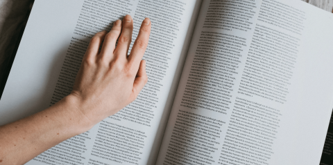 Hand scanning words on page of an open book