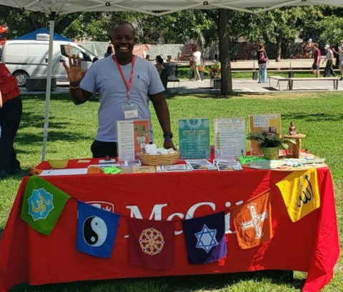 Tabletop display of MORSL collateral with multifaith flag banner, student staff
