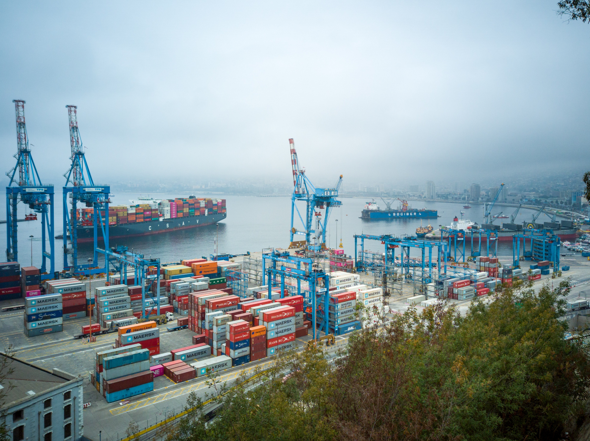 An busy urban port with many containers and container ships in the background