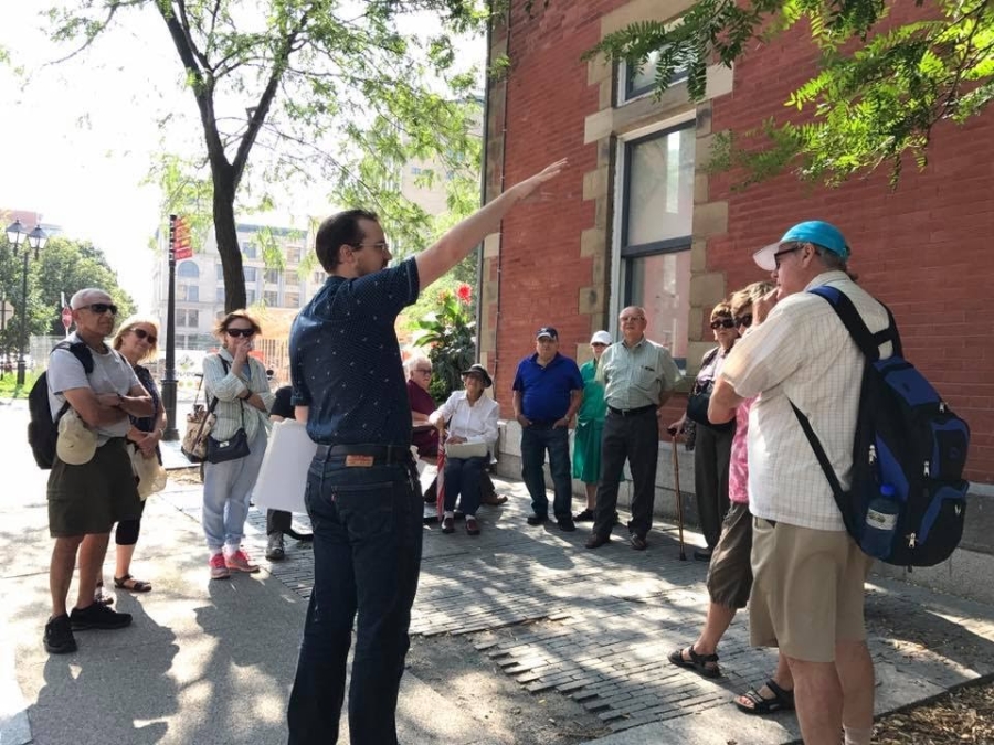people on a sidewalk listening to the tour guide