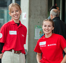 Two Schulich students wearing red t-shirts featuring the Schulich logo smile at the camera