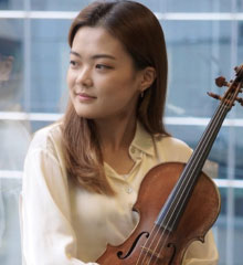 Young woman looks to the right and is holding a violin
