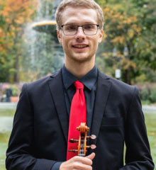 Smiling young man golds violin while looking at the camera