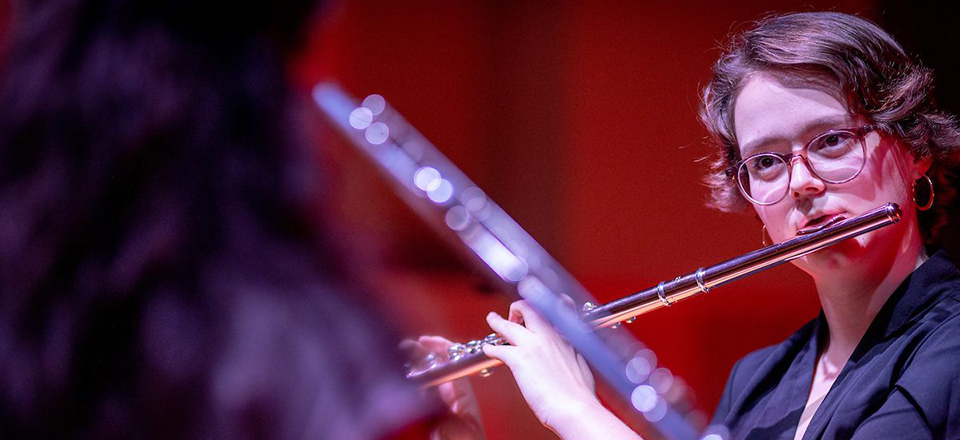 Student playing flute while looking at music score