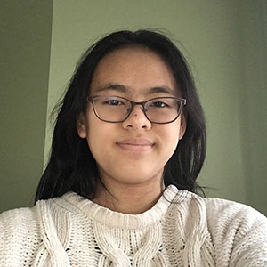 Woman with brown hair and wearing glasses smiles gently at the camera