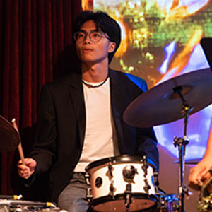 Man sits while playing drums