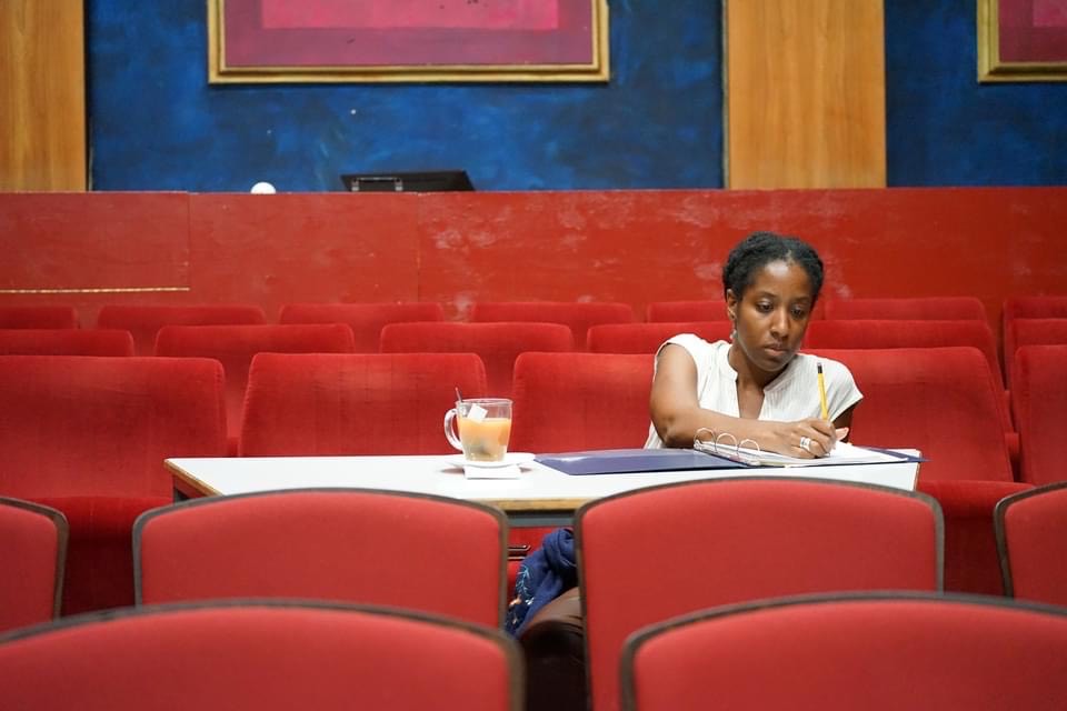 Sheree Spencer writing in binder, in theatre seats