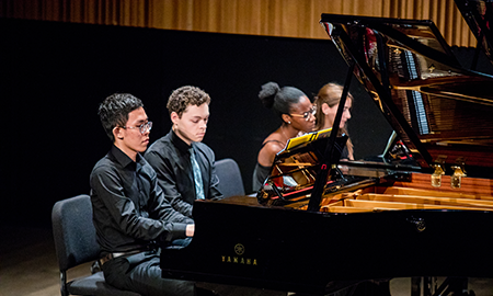 Four musicians playing at piano