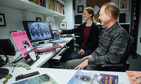 man and woman smiling while looking at a computer monitor