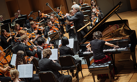 Orchestra playing with focus on Alexis Hauser conducting