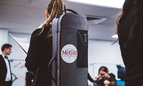 Musician carrying instrument case with schulich school of music logo
