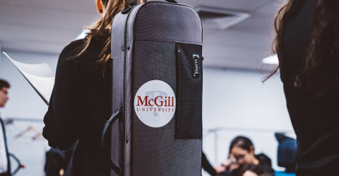 A woman carrying an instrument case with the McGill logo on it