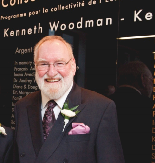 Kenneth Woodman stands front of the Donor Wall of the Kenneth Woodman Scholarship Fund.