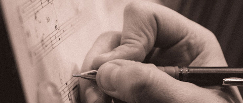 sepia filtered image of a hand holding a pen while writing 