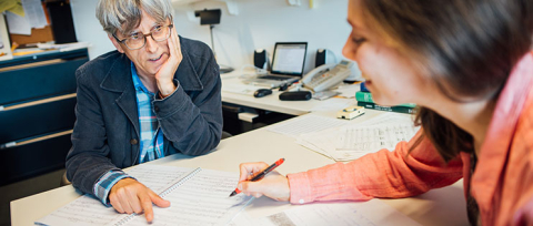 Man and woman sitting across from each other while looking a music composition score