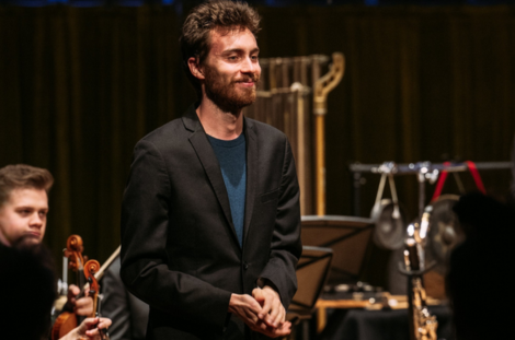 L'étudiant compositeur Kalen Smith salue l'orchestre derrière lui