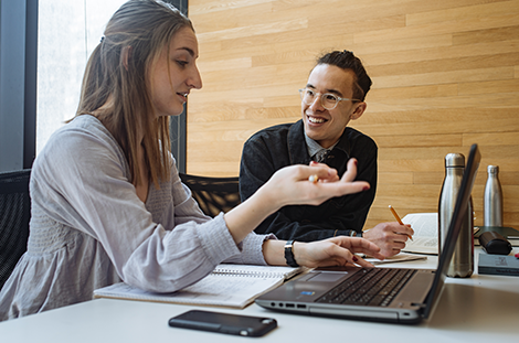 two people conversing and sharing information while looking at a laptop 