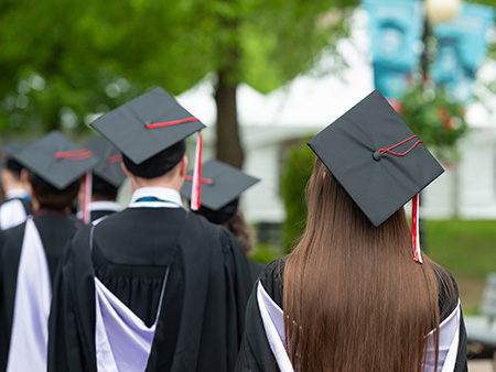 Student wearing mortar boards walking with backs to the camera