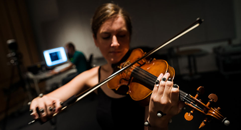 woman playing violin with sensors on fingers