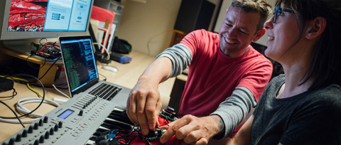 Man smiles as he reaches to adjust sound board