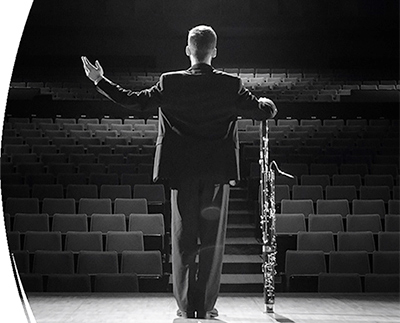 Male musician stands on stage looking out onto an empty auditorium