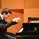 Alexey Shafirov playing piano with a happy look on his face
