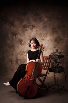 Photo of Wei-An Hung sitting while holding a cello