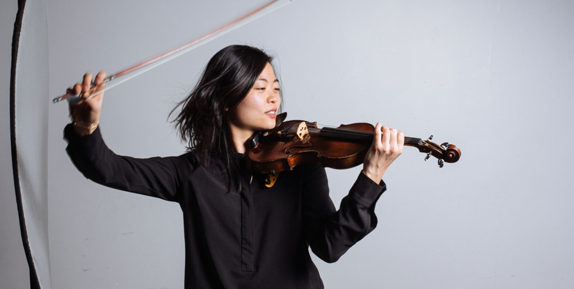 violin player makes dramatic pose with bow in the air