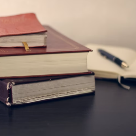 Stack of books with pen and paper