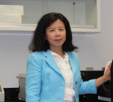 Lan Xiong in blue blazer next to lab machine