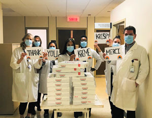 Members of the Social Service department pose in front of boxes of donuts with signs that read "Thank You Krispy Kreme"