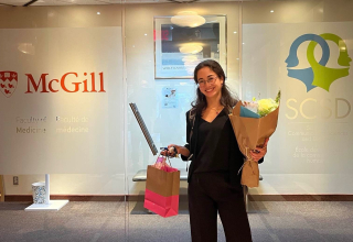 Dr. Honda after her thesis defense, posing with gifts in the school's lobby