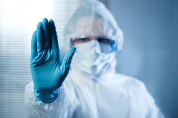Female scientist in protective hazmat suit with hand raised.