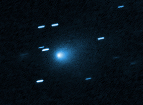 A blurry, blueish comet with a fuzzy tail against a black background.