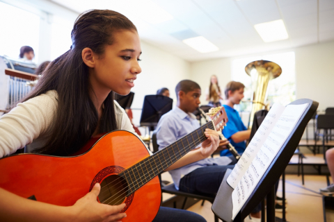 Student playing guitar in a high school orchestra