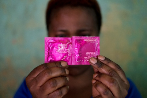 A sex worker conceals her face with a pack of condoms in the Katosi fishing village in Mukono, located east of Kampala, Uganda’s capital (October 24, 2019). Credit: E. Echwalu, UNAIDS, CC-BY 4.0 / Une travailleuse du sexe dissimule son visage derrière des emballages de préservatifs dans le village de pêcheurs de Katosi, dans le district de Mukono, à l’est de Kampala, la capitale de l’Ouganda (24 octobre 2019). Photo : E. Echwalu, UNAIDS, CC-BY 4.0