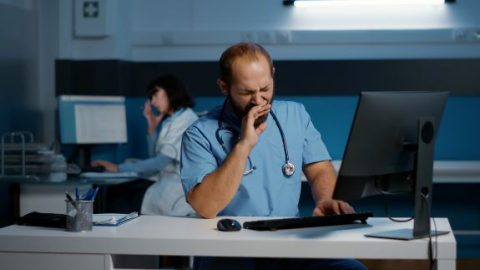 Tired medical work at a desk yawning