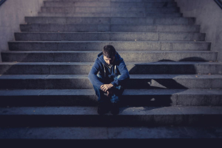 Sad young man sitting on stairs.